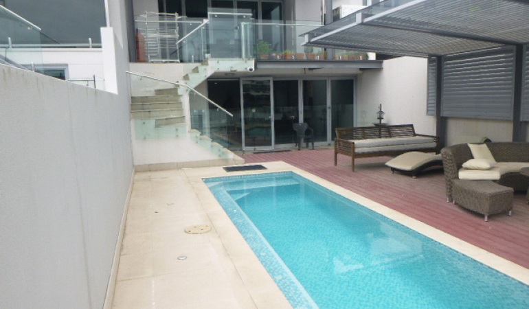 rectangular outdoor swimming pool with glass fencing