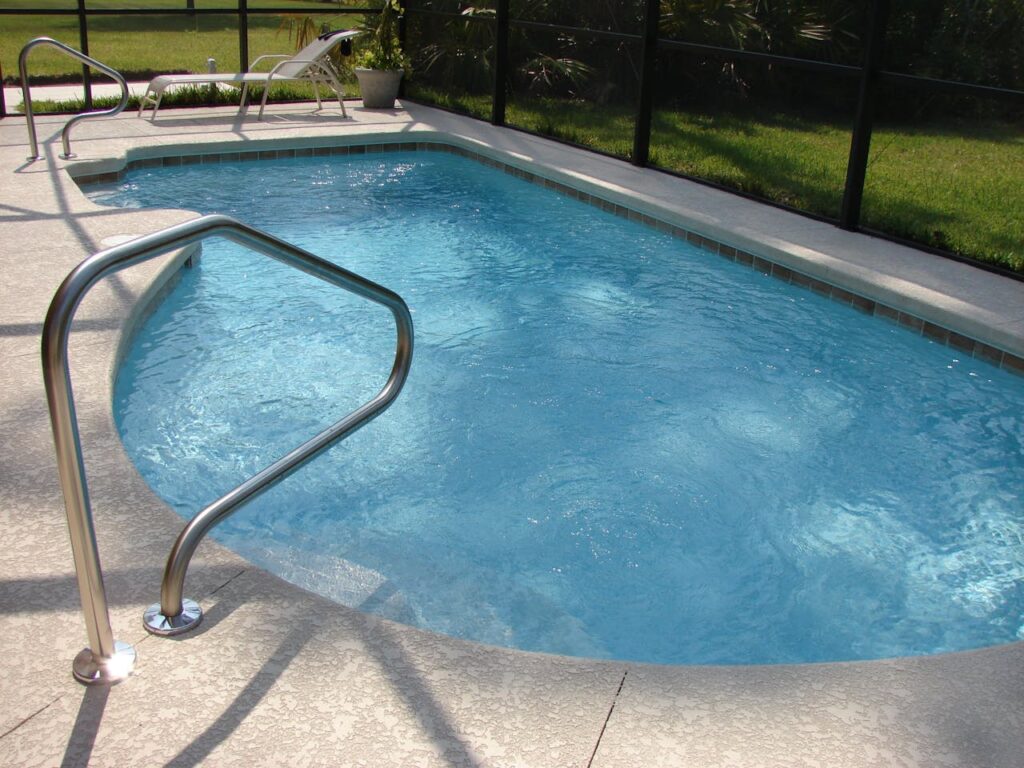 A residential backyard swimming pool with a textured deck, illustrating a typical installation and its potential cost.