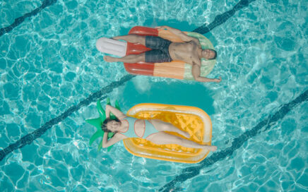 Two people relaxing on inflatable rafts in a swimming pool.