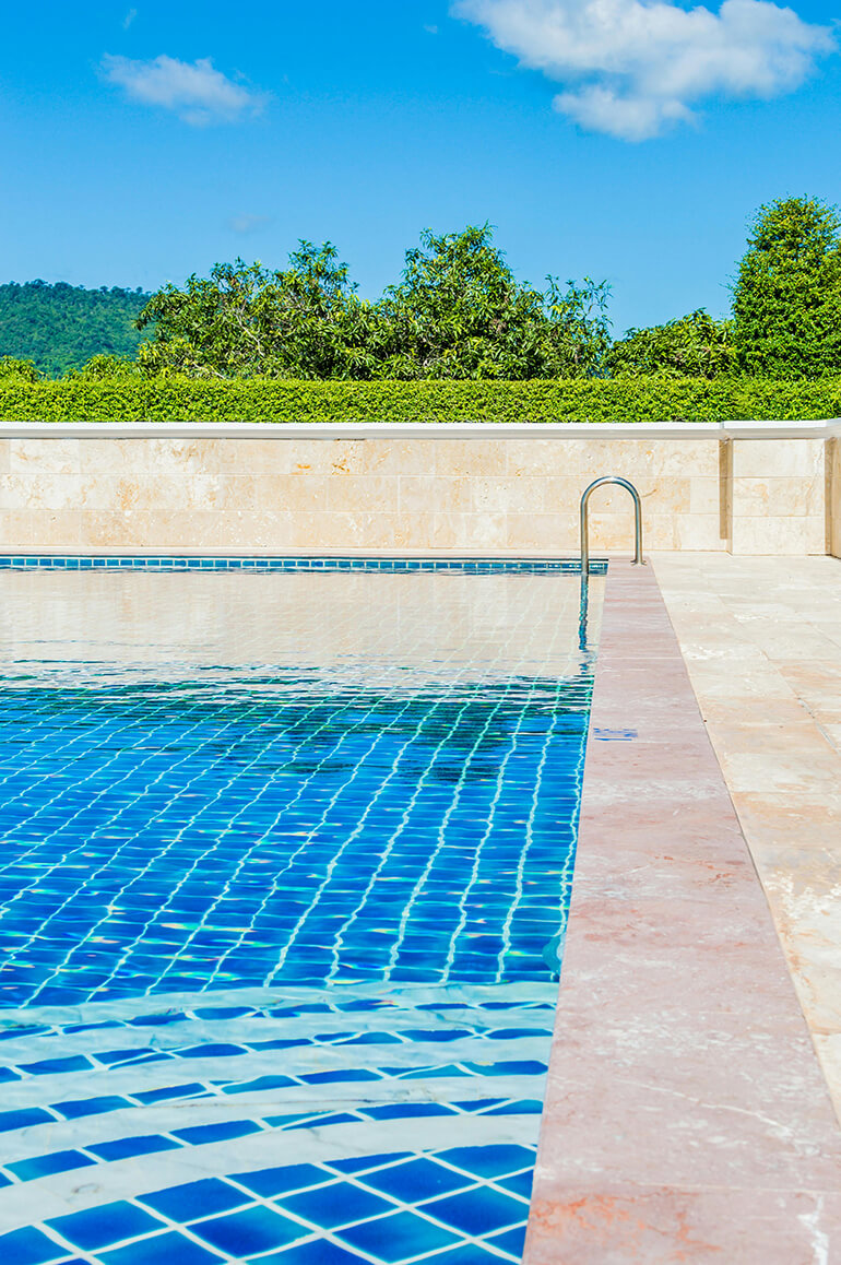 Clear blue swimming pool with trees and blue sky.